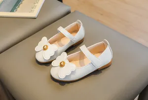Detail of white Mary Jane shoes with bow decoration, pearl accents, and Velcro strap