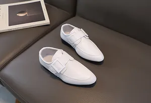 Dettaglio delle scarpe bianche da cerimonia per bambini in pelle sintetica lucida con fibbia