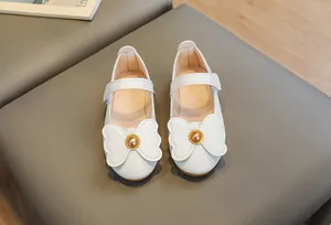 Close-up of white Mary Jane shoes for girls with bow decoration and velcro strap