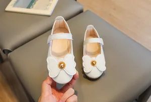 Close-up of girls white Mary Jane shoes featuring a bow and pearl charm detail