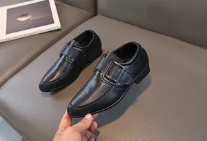Dettaglio delle scarpe eleganti da bambino nere opache con fibbia a strappo e suola in gomma