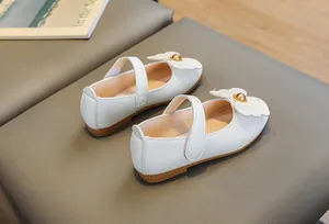 Detail of white Mary Jane girl shoes with wing patch and gold bead on soft rubber sole