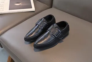 Dettaglio di scarpe stringate in pelle nera da bambino con chiusura a strappo su divano
