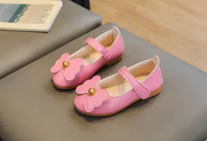 Detailed close-up of pink girls Mary Jane shoes with large bow and gold bead accent