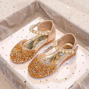 Détail de chaussures Mary Jane pour filles dorées avec strass et lanières de perles