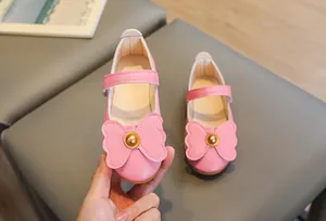 Close-up of pink girls Mary Jane shoes with leather bow and golden bead detail