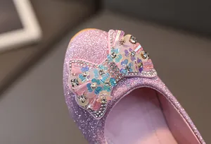 Close-up of pink glitter girls' shoes with a sequined bow and sparkling rhinestone details