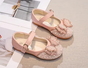 Detailed close-up of pink girls' princess shoe featuring pearl and rhinestone bow decoration