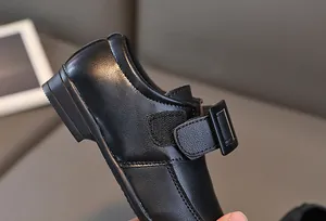 Dettaglio scarpa formale in pelle nera per bambini con cinturino a strappo