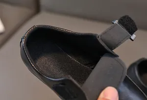 Dettaglio di scarpe in pelle nera per bambini con pratica chiusura a strappo regolabile