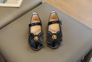 Detail of girls' black Mary Jane shoes with textured bow and golden bead accent