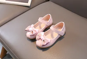 Close-up of pink patent leather Mary Jane shoes with glittery bow and rubber sole