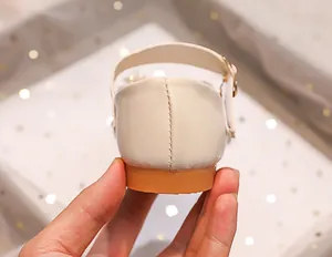 Detail view of girls' white princess shoes featuring fine heel stitching and a gold buckle