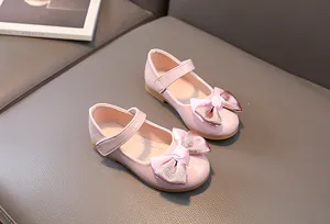 Pink patent leather Mary Jane shoes for girls featuring a glitter bow and velcro strap