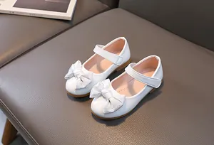 Close-up of white Mary Jane shoes featuring shiny patent leather and bow detail