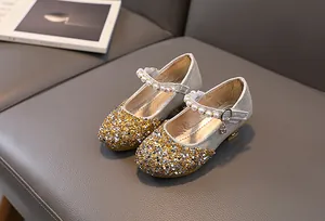 Detail of girls' champagne glitter princess shoes with pearl straps and rhinestone charms