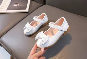 Detail of white girls' Mary Jane shoes featuring a glittery silver bow and velcro strap