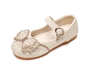 Detail of girls princess shoes with shiny rhinestones pearls and bowknot on beige PU leather