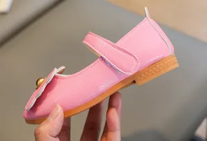Detail of pink girls Mary Jane shoe with bow buckle and textured leather side view