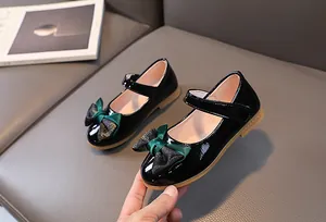 Detail of glossy black Mary Jane shoes with dual-material bow and non-slip rubber sole