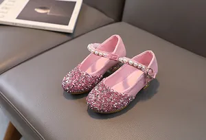 Close-up of pink glitter girls princess shoes with faux pearls and golden buckle details
