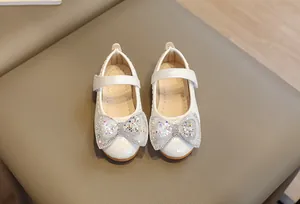 Dettaglio scarpe Mary Jane in pelle bianca con fiocco di paillettes e cinturino velcro