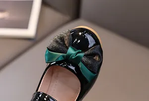 Detail of girls black patent leather Mary Jane shoes with elegant double-layered bows