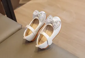 Dettaglio scarpe Mary Jane bianche con fiocco di strass e trama intrecciata lucida