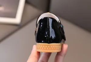 Close-up of black patent leather girls shoe with anti-slip rubber sole and heel stitching