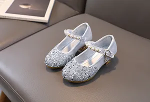 Detailed view of silver sequined Mary Jane shoes with pearl strap and rhinestone charm
