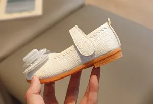 Dettaglio di scarpe Mary Jane bianche con fiore a rete, strass e perle fini