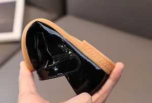 Close-up showing the flexible rubber sole of kids patent leather bow princess shoes