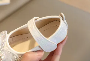 Dettaglio scarpe Mary Jane bianche da bambina con trama intrecciata e fiocco