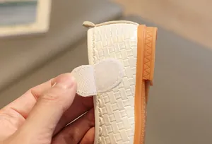 Dettaglio di scarpe bianche da bambina con trama intrecciata e chiusura a strappo