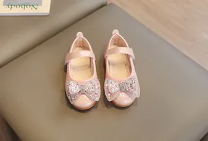Dettaglio di scarpe Mary Jane rosa con fiocco di paillettes e trama intrecciata