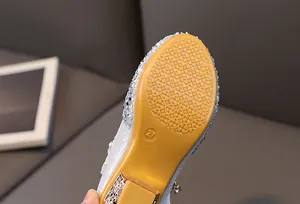 Close-up of non-slip golden rubber sole on sparkling silver sequin princess shoes