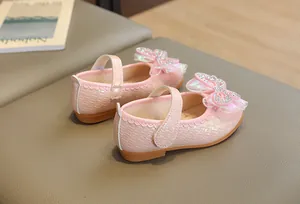 Close-up of pink girls princess shoes with mesh bow, sparkling rhinestones and woven texture