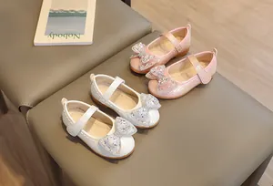 Dettaglio di scarpe Mary Jane rosa e bianche per bambine con fiocco di strass e velcro