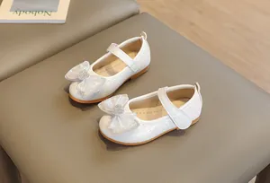 Close-up of girls' white Mary Jane shoes with heart rhinestone and organza bow detail
