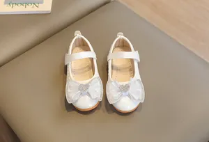Close-up of white girls Mary Jane shoes with mesh bow, rhinestone heart and croc texture