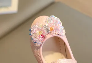 Gros plan d'une chaussure rose pour fille avec nœud en paillettes arc-en-ciel et strass