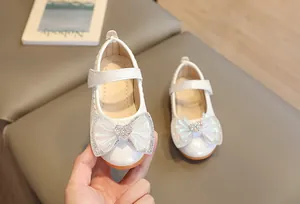 Detail of white girls' Mary Janes with quilted texture and rhinestone heart bow