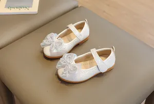 Detail view of girls' white Mary Jane shoes featuring a rhinestone organza bow and woven texture