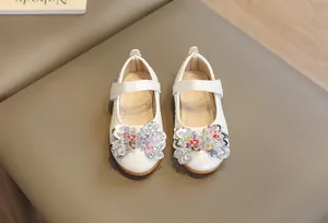Détail de chaussures en cuir blanc pour filles avec texture croco et nœud brillant