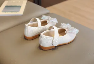 Detail of white girls Mary Jane shoe with sequined bow and woven texture detail