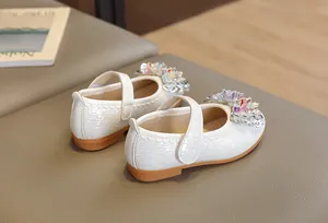 Détail de chaussures Mary Jane blanches pour filles avec texture tissée et fleurs en cristal