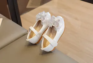 Detail of white girls Mary Jane shoe with mesh bow, sparkling rhinestones and velcro strap