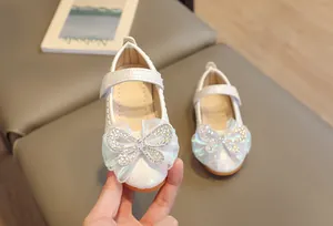 Close-up of pearl white Mary Jane shoe with mesh rhinestone bow and velcro strap
