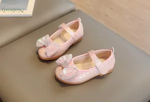Close-up of pink girls Mary Jane shoes with glitter bow and woven texture detail