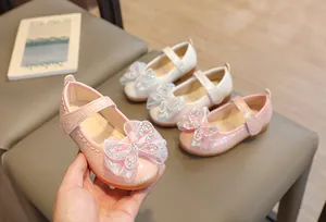 Detail of pink and white girls Mary Jane shoes with rhinestone bow and sequin accents